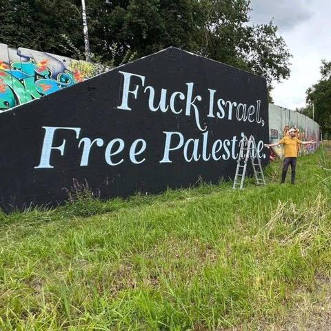 A large wall painted black with the words FUCK ISRAEL, FREE PALESTINE painted in big white letters