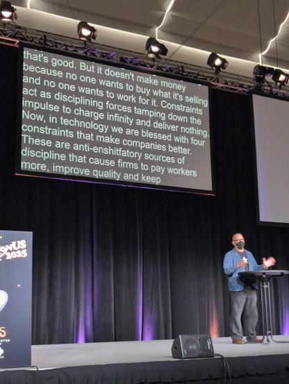 Cory Doctorow on stage in front of captions containing the word "anti-enshitfatory"