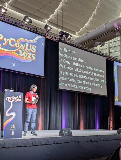 Elaine stands on the stage at PyCon US, the caption monitor reads "Well, hope FAEG you don't feel as tired"