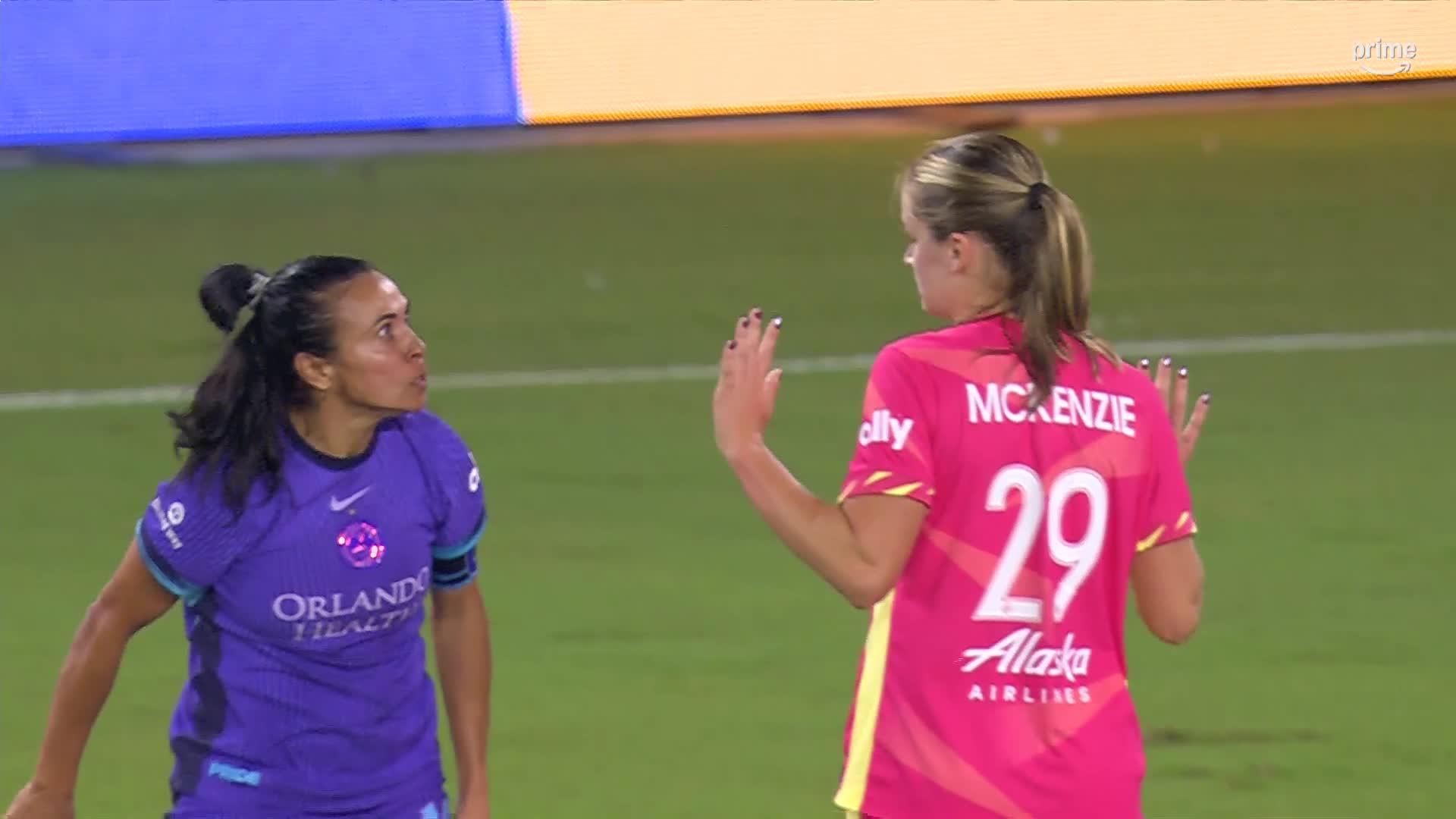 a different view of Marta staring down McKenzie, who has her arms raised in a 'not me' gesture