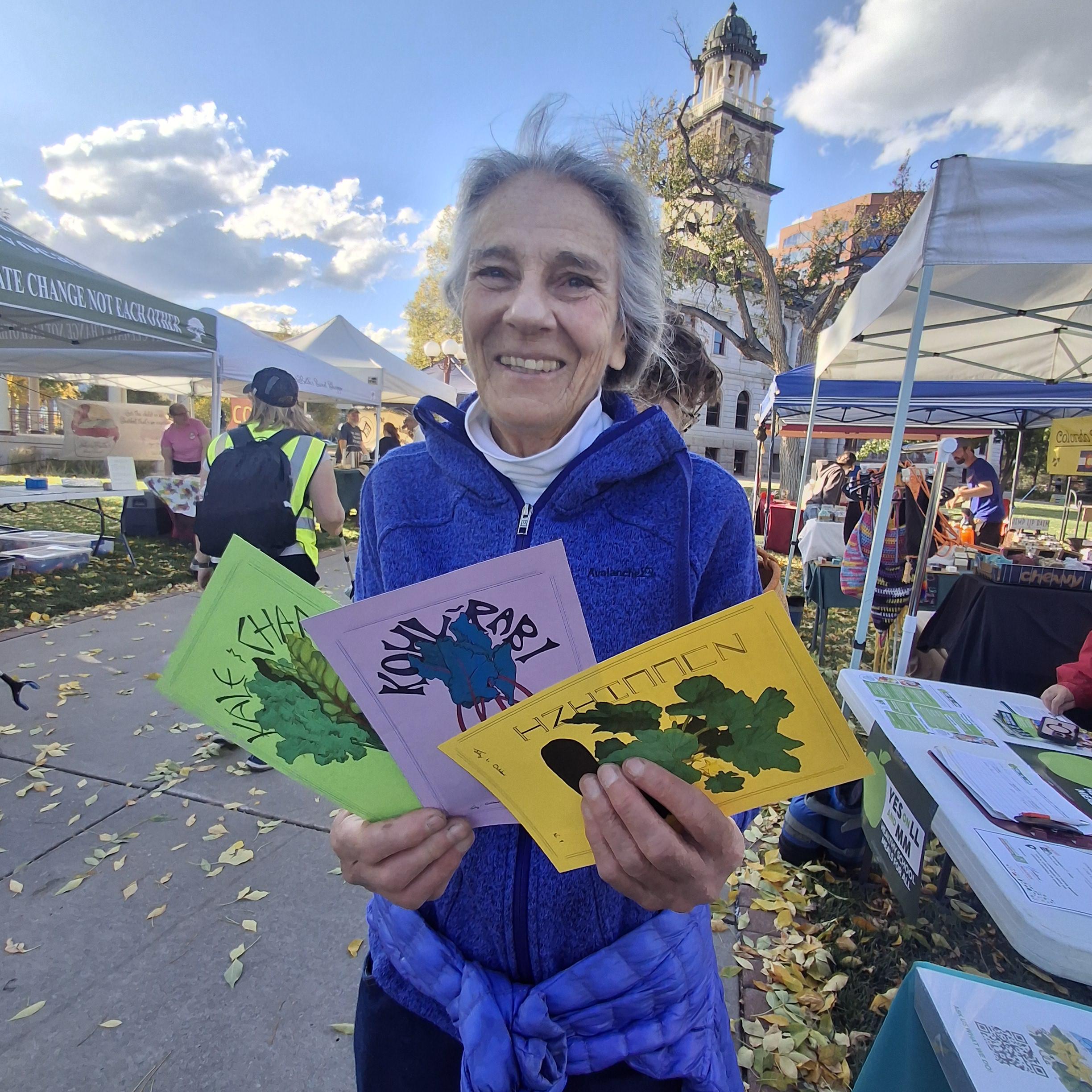 Elderly person holding colorful pictures, standing in front of a courthouse on a sunny afternoon 