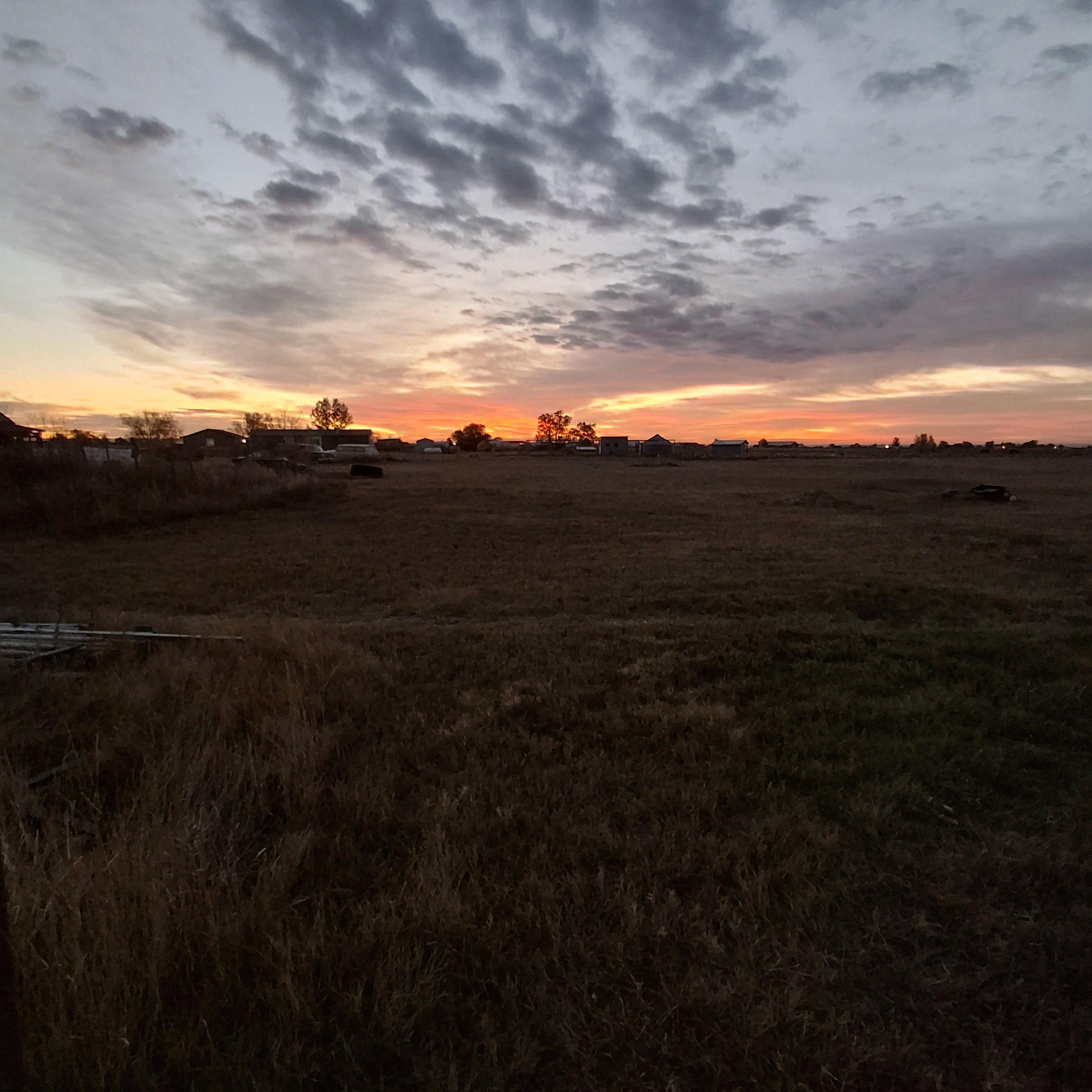 Red skyline over the October prairie. Roosters crowing and dogs barking.