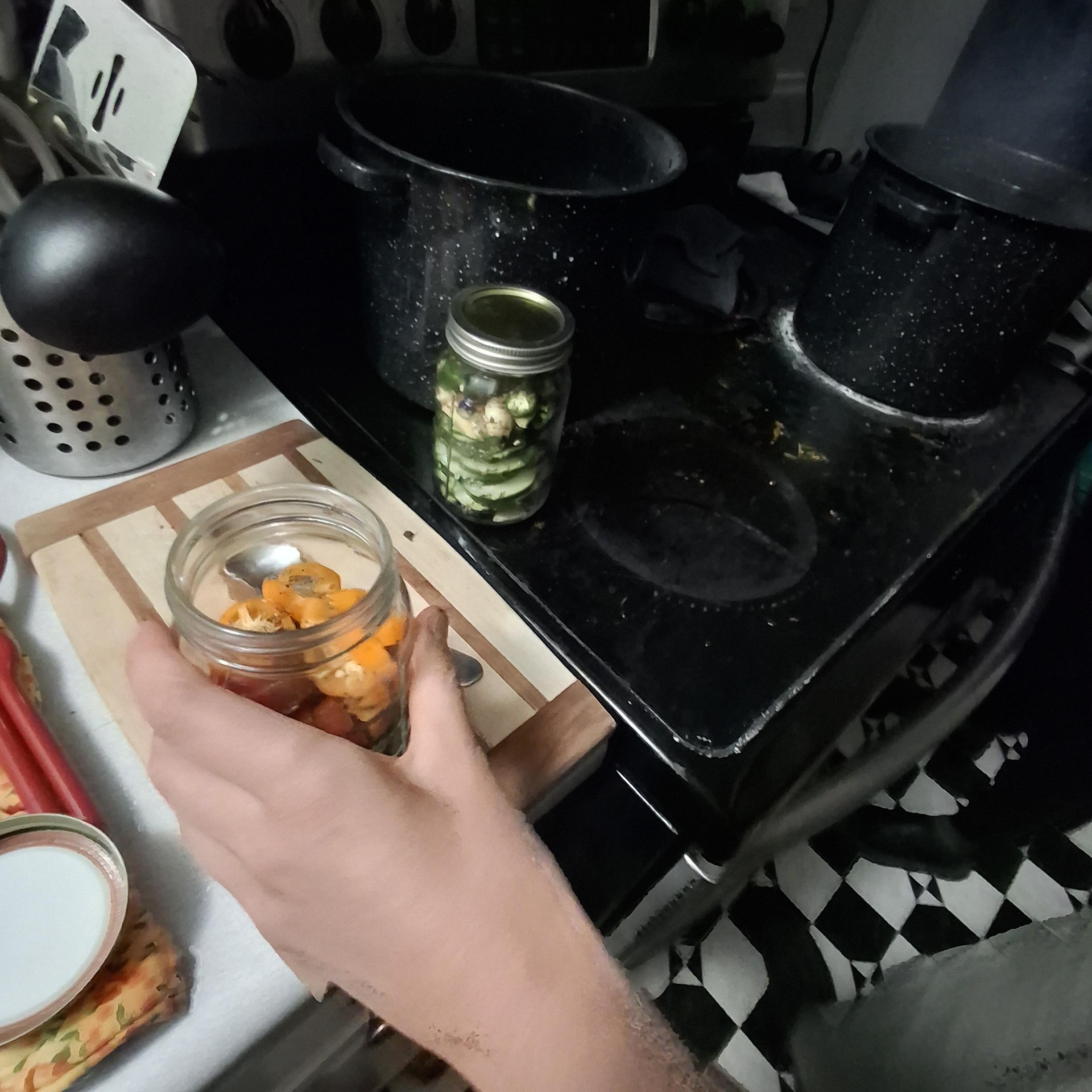 Hand holding jar awaiting brine, sealed jar ready for boiling.