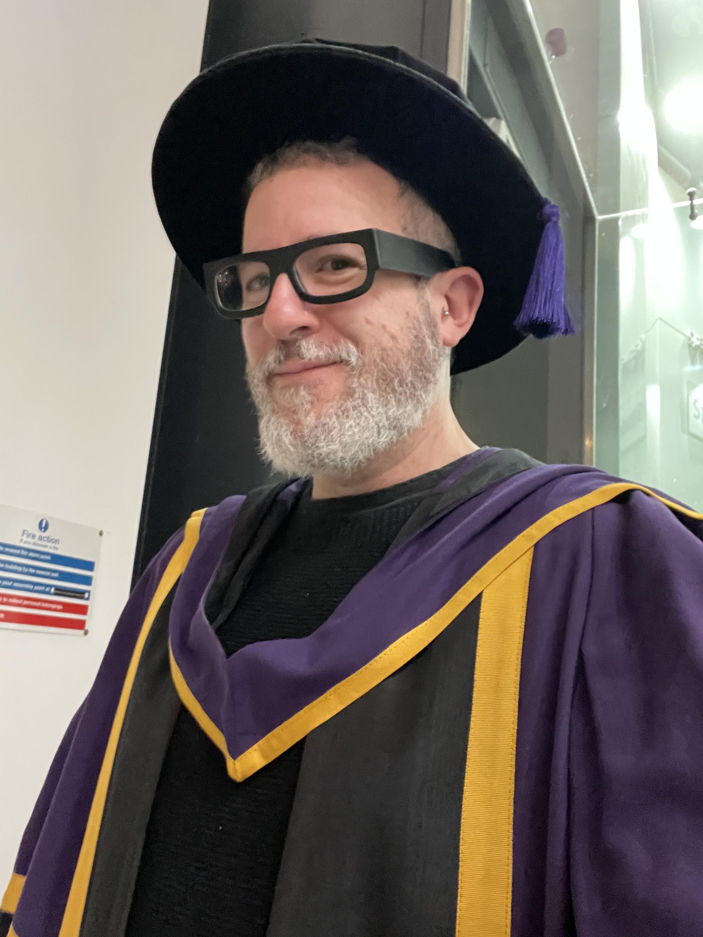 Yr humble narrator, in the robes of an actual motherfunky Doctor of Philosophy, upon graduation from yon London School of Economics and Political Science, London, December 16th, 2025. I’m not nearly as smug as this facial expression suggests, I promise.
