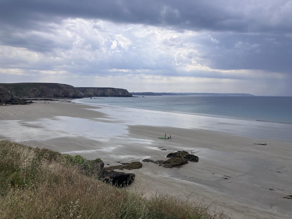 Photo taken from Pen Hir, Camaret, overlooking Pen Hir Cove. The tide is low, and more importantly, rain and thunderstorms are approaching. The sky is gray and very cloudy, with cumulonimbus clouds signaling an approaching thunderstorm.